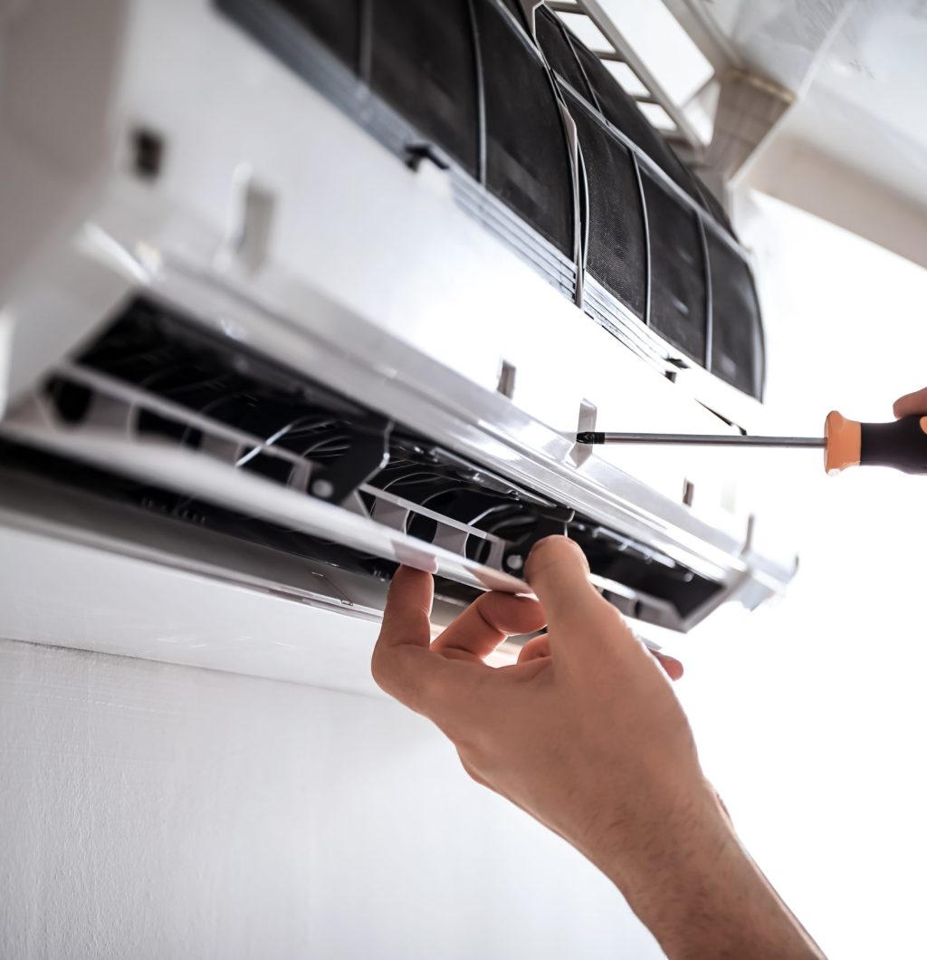 A technician repairing a wall-mounted air conditioning unit