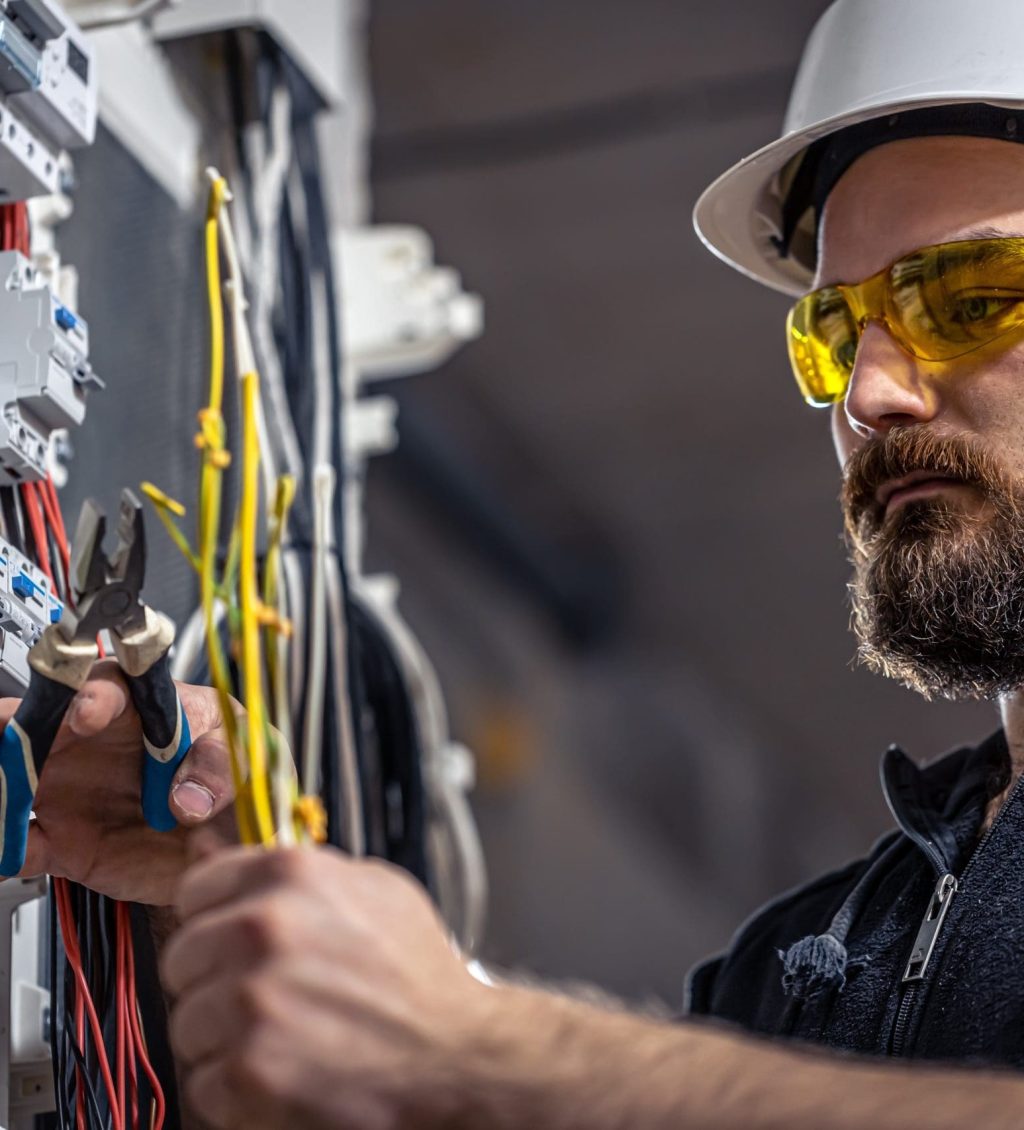 An electrician cutting cables in a distribution board