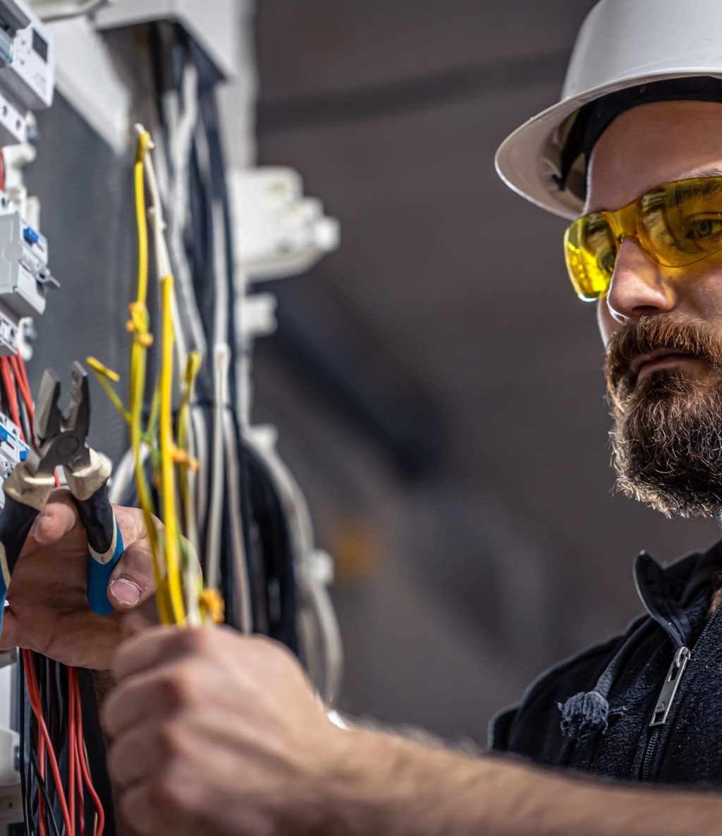 An electrician cutting cables in a distribution board
