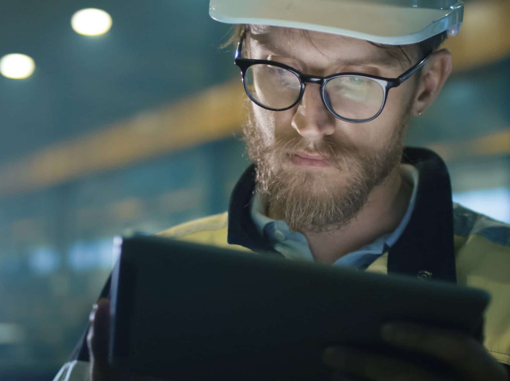 Engineer in glasses and white hard hat completing work on writing pad